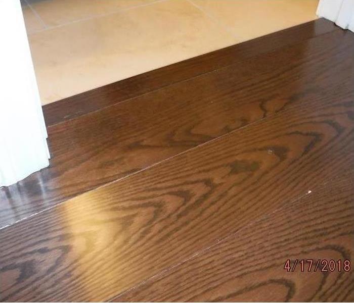 The image shows water damage to a hard wood floor