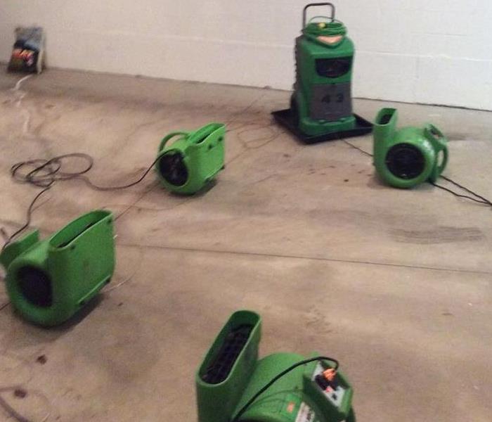 Photo shows drying equipment consisting of air movers and dehumidifiers drying out a building
