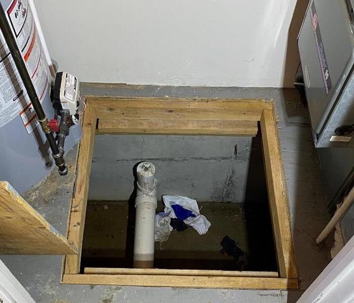 A photo showing a crawl space opening with standing water